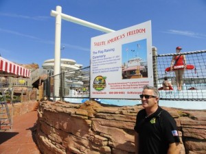 General Manager Ed Myers stands beneath a sign explaining the park's daily flag-raising tradition.