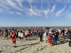 A crowd of competitors and spectators listens to the opening ceremonies of the Memorial Beach Challenge early on Saturday, May 23.
