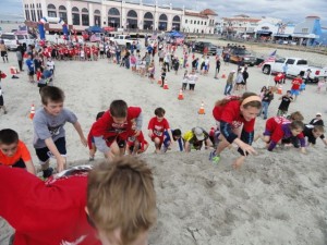 Kids climb makeshift sand mounds as part of the fun run in the Memorial Beach Challenge.