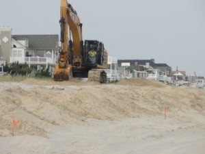 An excavator is at work shaping dunes between 56th Street and 57th Street.