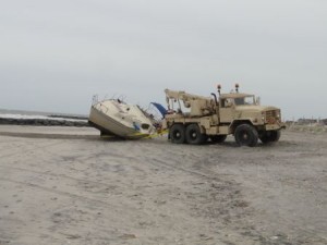 An Ocean City Fire Department vehicle on Tuesday helps move a boat that was stranded on the beach Saturday beyond the tideline at Seaspray Beach.