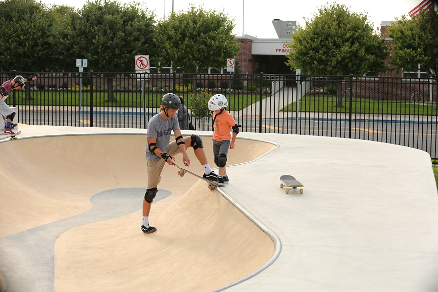A counselor instructs a young skater in the snake run at the FCA Skate Camp.