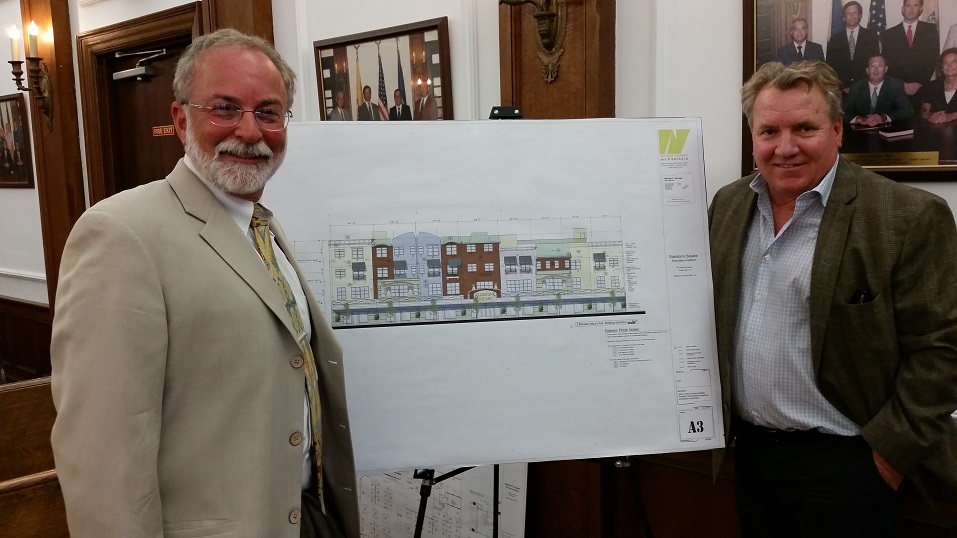 Developers Brett Foxman, left, and Lester Argus stand in front of an architectural rendering of their project.
