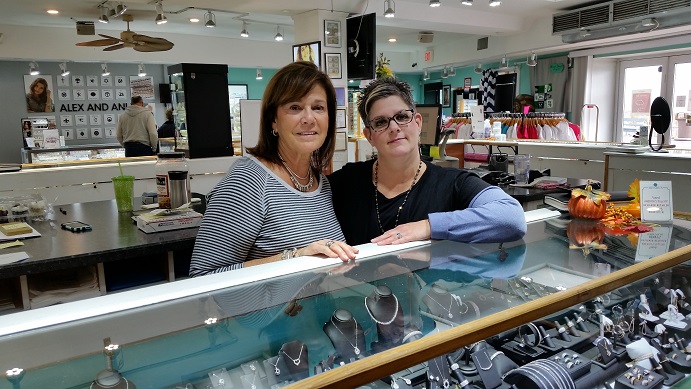 Saleswomen Marianne D'Elia, left, and Kate Harris greet customers at a jewelry counter.