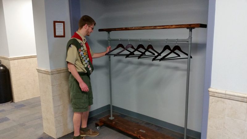 Andrew places the coat rack in a cubbyhole along the hallway at the library's 17th Street entrance.